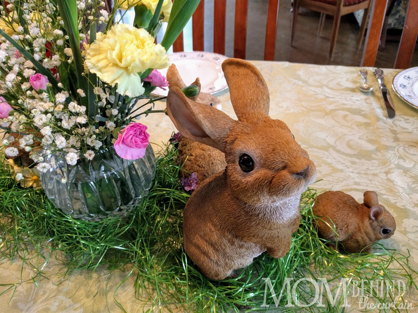 Easter rabbit collection arranged with real flowers and Easter basket grass.